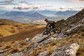 A biker barreling down a rocky trail on a mountain in New Zealand.
